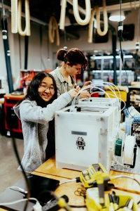 Two students working on a printer.