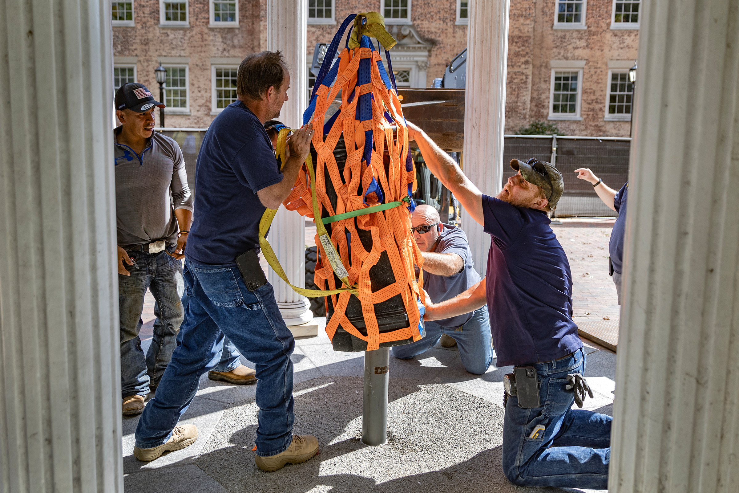 Workers putting a fountain into place above a well.