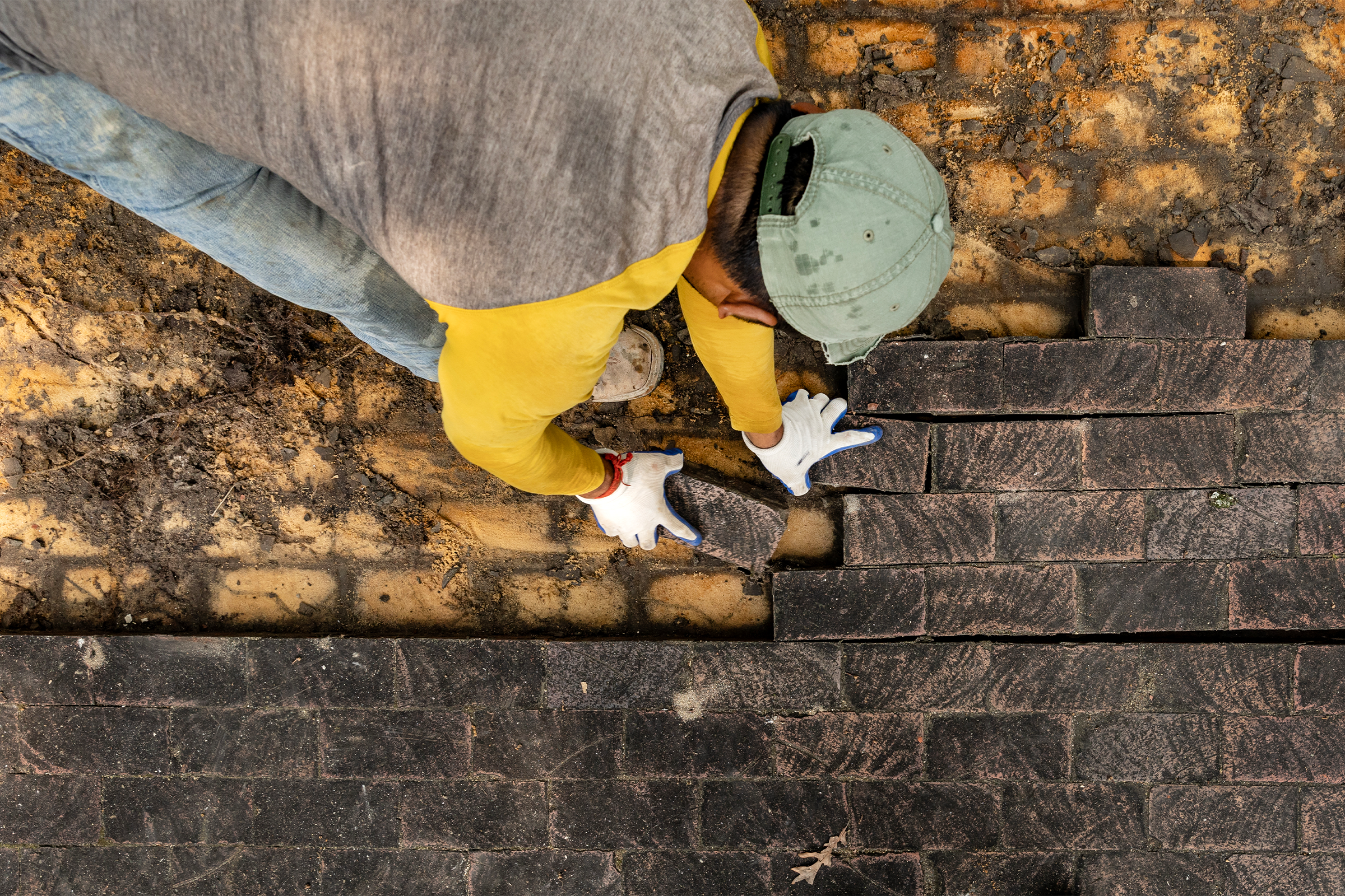 Aerial view of a worker removing bricks from the ground.