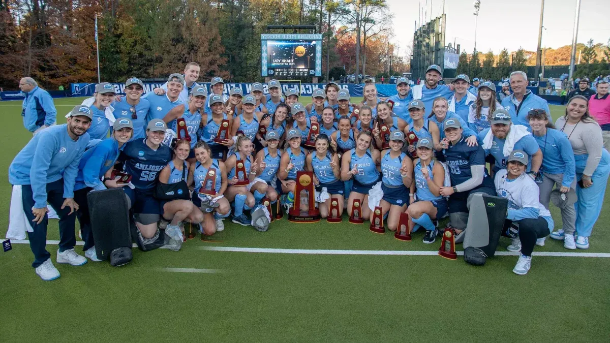 The Carolina field hockey team posing for a team photo with the NCAA championship trophy on the field at Karen Shelton Stadium on the campus of UNC-Chapel Hill