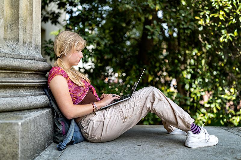 A student using her laptop outside Wilson Library on the campus of UNC-Chapel Hill.