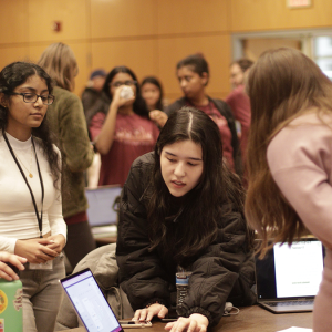 Group of Pearl Hacks attendees gathering around a laptop to examine a project.