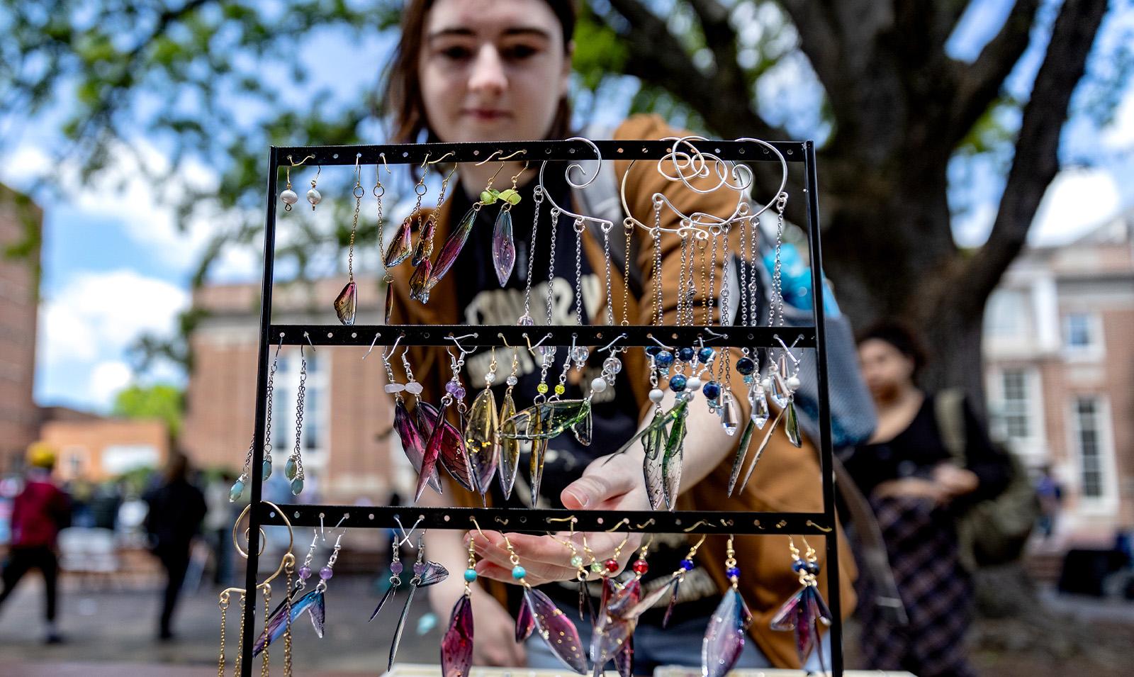 A student looking at a piece of art featuring jewelry hanging from a line.