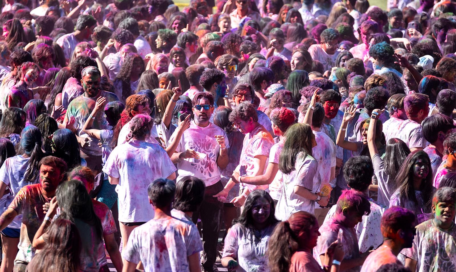 Crowd of students on a field celebrating Holi