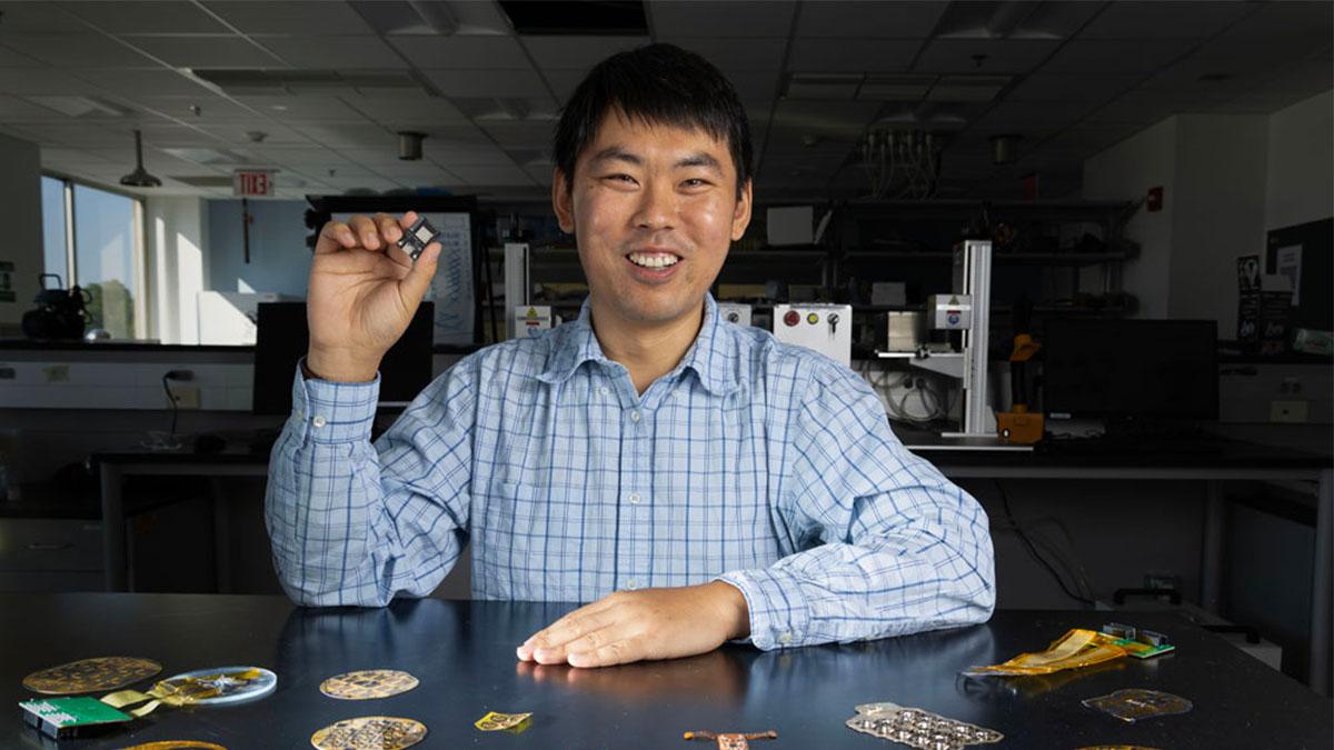 Wubin Bai in a lab holding a device he created.